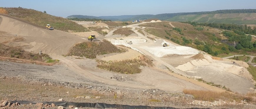  Eine Deponie, die von Radladern befahren wird und teilweise mit Gras bewachsen ist