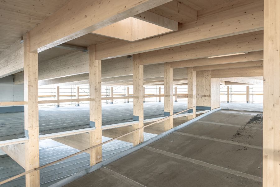  Innenansicht der Auffahrt im Holzparkhaus. Der Fahrbahnbelag ist betoniert, die gesamte Struktur ist in Holzbauweise.