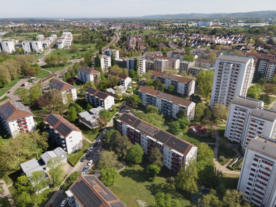  Luftansicht des Wohnviertels, in dem sich die Garagenaufstockung befindet. Am rechten Bildrand befinden sich drei Wohn-Hochhäuser, links daneben mehrere vier- bis fünfgeschössige längliche Wohnhäuser. Im Hintergrund ist der Beginn des Nordschwarzwaldes zu sehen.