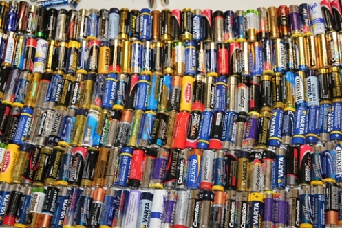 Verschiedene Alltagsbatterien in Reihen auf einer Tischplatte ausgelegt