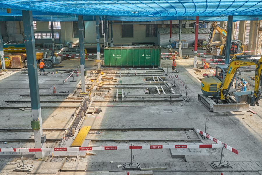 Blick auf die Baustelle. Rechts und rechts hinten jeweils Schaufelbagger, in der Bildmitte ein grüner Schuttcontainer. Die Decke ist mit blauem Gitternetz abgehängt. Blick auf die Baustelle. Rechts und rechts hinten jeweils Schaufelbagger, in der Bildmitte ein grüner Schuttcontainer. Die Decke ist mit blauem Gitternetz abgehängt.