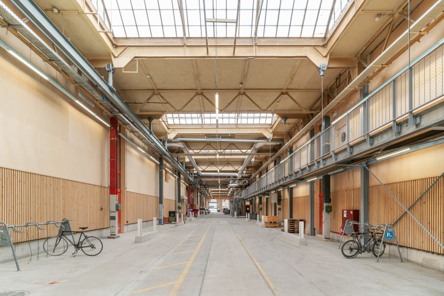 Blick in die fertiggestellte Halle in Längsrichtung. Die Wände links und rechts sind bis in etwa zwei Meter höhe mit Holz verkleidet. Die giebelfüörmigen in Querrichtung angebrachten Oberlichter lassen viel Licht in die Halle. Blick in die fertiggestellte Halle in Längsrichtung. Die Wände links und rechts sind bis in etwa zwei Meter höhe mit Holz verkleidet. Die giebelfüörmigen in Querrichtung angebrachten Oberlichter lassen viel Licht in die Halle.