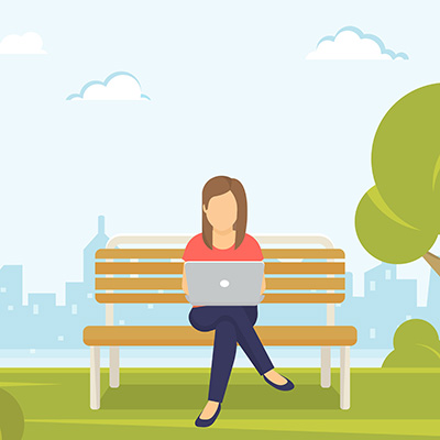 Frau sitzt auf Parkbank mit Laptop auf dem Schoß.