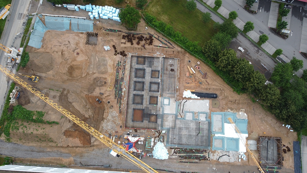 Drohnenflug im Juni über die Baustelle. Im Vordergrund ist der Kran zu sehen. Rechts ist das Fundament des Laborgebäudes in Teilen gegossen. in Teilen 