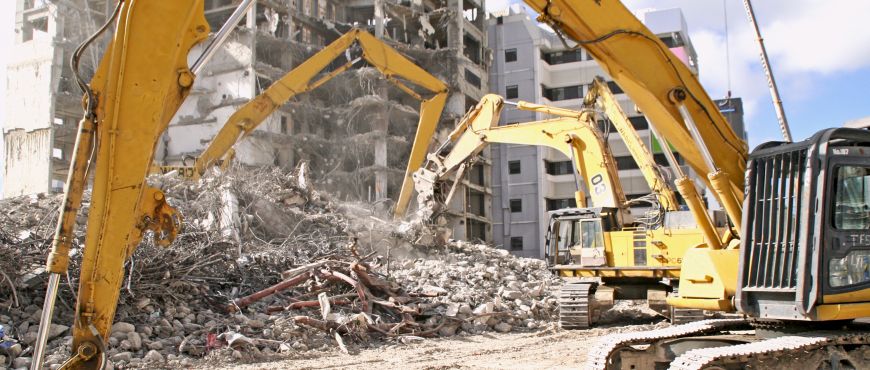 Drei Abbruchbagger reißen ein Hochhaus ab.